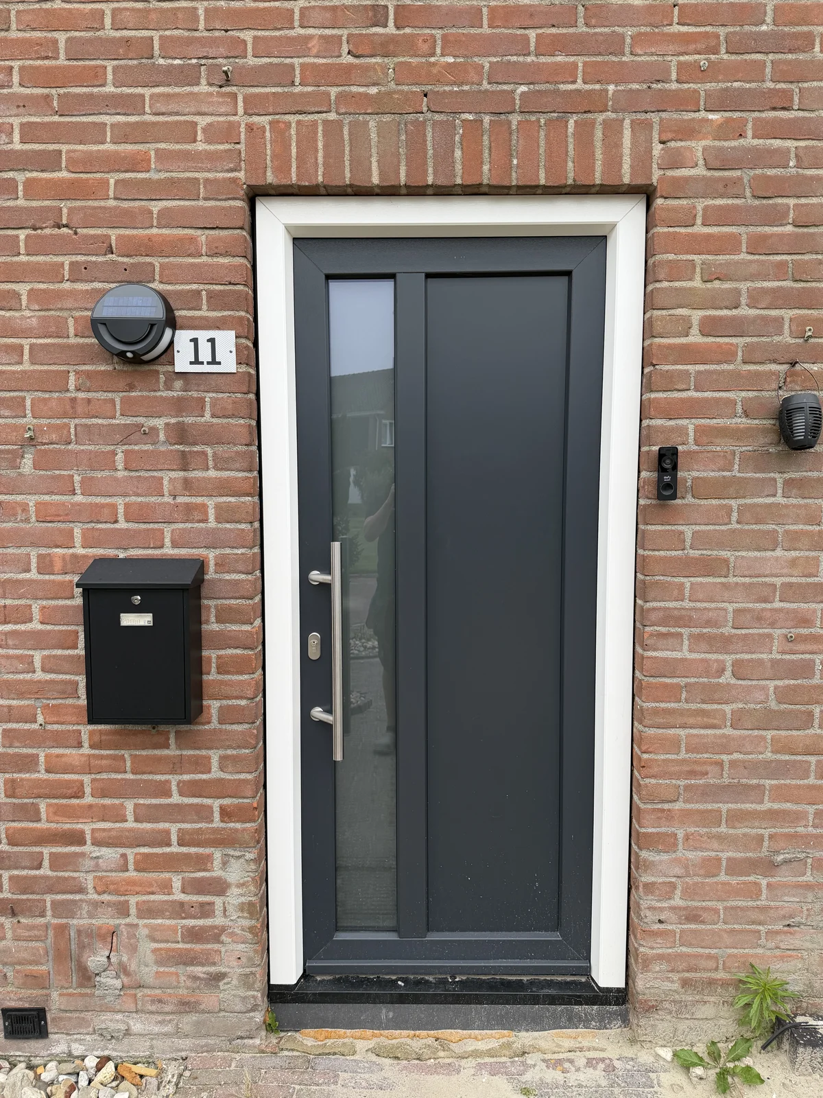Donkere kunststof voordeur met een smal verticaal glasvak